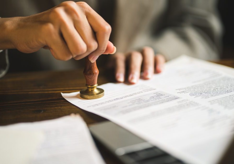 close-up of person stamping documents to approve agreements,